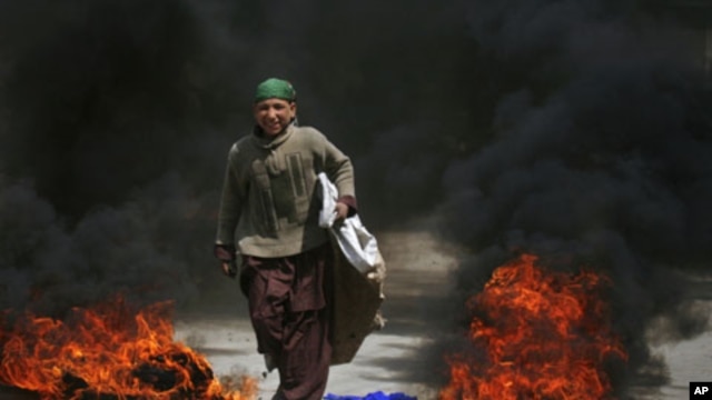 A boy walks past tires set ablaze by protesters following a shootout by unidentified gunmen in Pakistan's southwestern city of Quetta, March 29, 2012. 