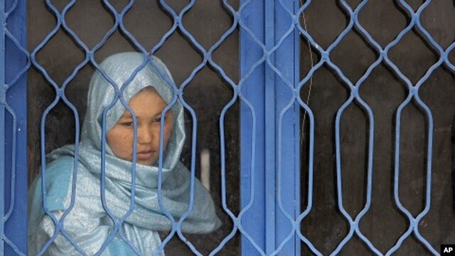 An Afghan inmate watches from behind a barred window during a media event at a women's prison in Kabul. (File Photo - March 30, 2010)