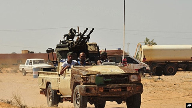 Anti-Gadhafi fighters ride a pick-up truck with an anti-aircraft gun attached to it toward Sirte, September 10, 2011