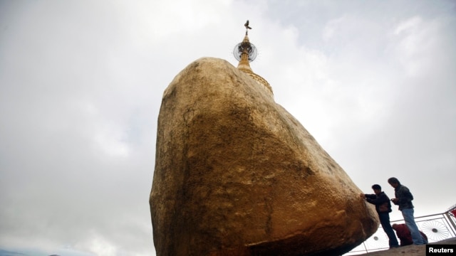 Buddhist devotees give offerings at the Kyaikhtiyo Pagoda, also known as the Golden Rock Pagoda, (File photo).