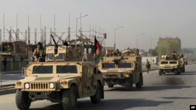 Afghan security personnel leave the area after a battle with Taliban insurgents who took over a building in Kabul, April 16, 2012.