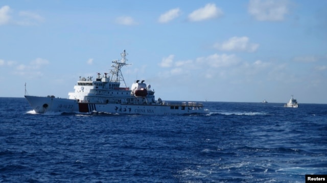 FILE - Chinese ships chase Vietnamese vessels, not shown, after they came within 10 nautical miles of a Chinese oil rig in the South China Sea, July 15, 2014.
