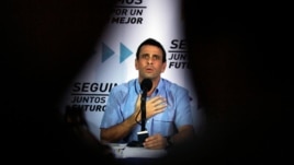 El líder de la oposición venezolana Henrique Capriles es flanqueado por las siluetas de los periodistas.