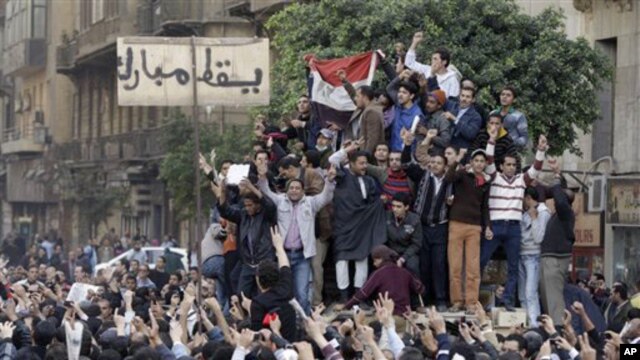 Egyptian anti-government protesters climb atop an Egyptian army armored personnel carrier, next to a signpost bearing the words "Down Mubarak", in Cairo,January 29, 2011