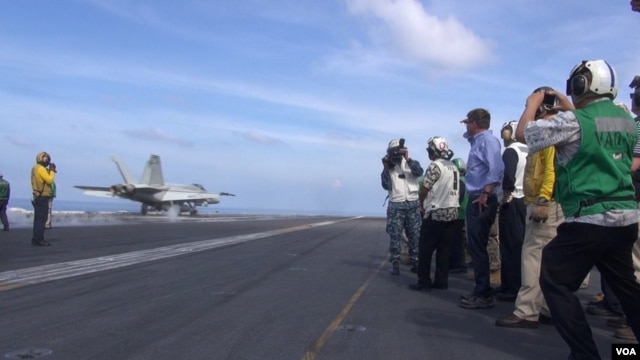 Bộ trưởng Quốc phòng Mỹ Ash Carter (mặc áo sơ-mi xanh, ở giữa) xem phi cơ cất cánh từ hàng không mẫu hạm USS John C. Stennis ở Biển Đông ngày 15/4/2016.