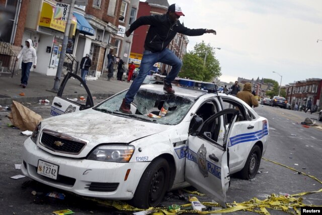 Người biểu tình giẫm lên xe cảnh sát Baltimore bị hư hại trong các vụ bạo loạn ngày 27/4/2015.