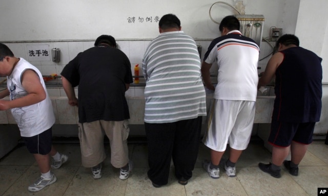 FILE - In this July 24, 2008, file photo, obese patients wash their plates after lunch at the Aimin Fat Reduction Hospital in Tianjin, China. A study released at that time said China had surpassed some richer countries long plagued with diabetes to develop the world's biggest epidemic.