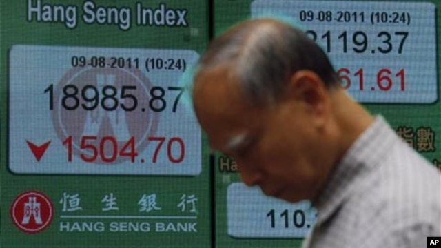 A man passes a screen displaying the Hong Kong Stock index, Aug. 2011 (file photo).