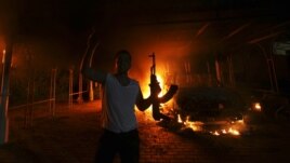 A protester reacts as the U.S. Consulate in Benghazi is seen in flames during a protest by an armed group said to have been protesting a film being produced in the United States September 11, 2012. 