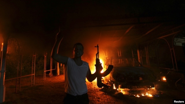 A protester reacts as the U.S. Consulate in Benghazi is seen in flames during a protest by an armed group said to have been protesting a film being produced in the United States September 11, 2012.