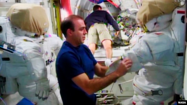 Expedition 38 crew member Rick Mastracchio (L) checks out the spacesuit that he will wear during a spacewalk with crew member Mike Hopkins, in the Quest airlock in the International Space Station in this undated image taken from video from NASA TV, Dec. 20, 2013.