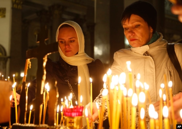 People light candles inside an Orthodox church in St.Petersburg during a day of national mourning for the plane crash victims, Russia, Nov. 1, 2015.