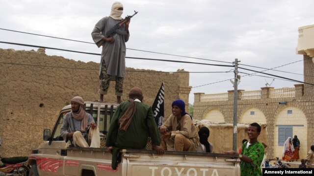 Fighters from Islamist group Ansar Dine stand guard as they prepare to publicly lash a member of the Islamic Police found guilty of adultery, in Timbuktu, Mali. (Aug 31, 2012 file photo)
