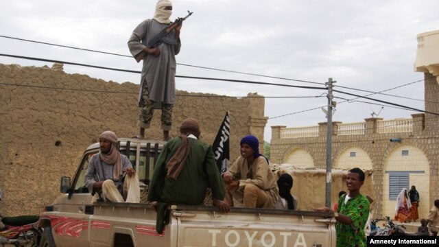 Fighters from Islamist group Ansar Dine stand guard as they prepare to publicly lash a member of the Islamic Police found guilty of adultery, in Timbuktu, Mali, Aug 31, 2012.
