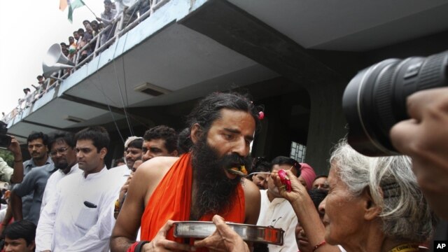 An old Indian woman offers food to yoga guru Baba Ramdev to break his fast in New Delhi, India, Aug. 14, 2012. 