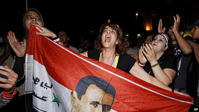 Supporters of Syrian President Bashar al-Assad shout slogans holding their country's flag with a superimposed Assad portrait, Damascus, Syria, August 20, 2011.
