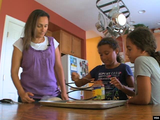 Wafaa Elmahgob cooks with her daughter, Nourene Nabbus, and her niece. (VOA)