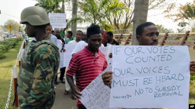 Protesters walk past a soldier standing guard during a rally against the decision to end fuel subsidies in Nigeria's capital Abuja, January 6, 2012.