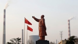 A statue of former Chinese leader Mao Zedong is seen in front of smoking chimneys at Wuhan Iron And Steel Corp in Wuhan, Hubei province, Mar. 6, 2013.