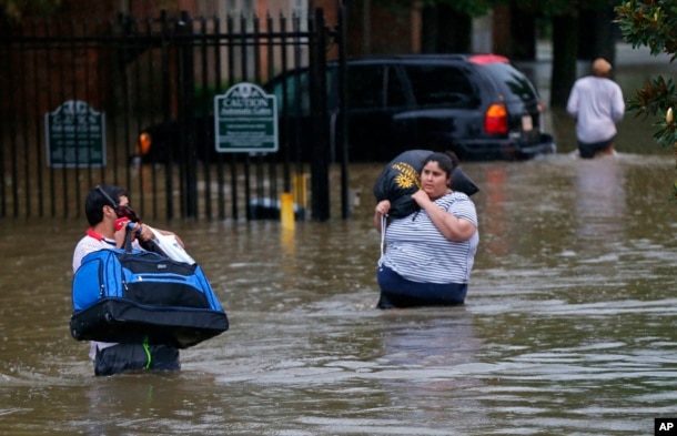 FILE - Residents wade through floodwater in the Chateau Wein Apartments in Baton Rouge, Louisiana, Aug. 12, 2016.