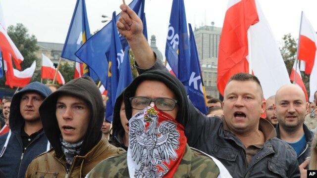 FILE - Protesters shout anti-migrant slogans as several thousand right-wing nationalists rally, demonstrating against EU proposed quotas for Poland to spread the human tide of refugees around Europe, in Warsaw, Poland, Sept. 12, 2015.