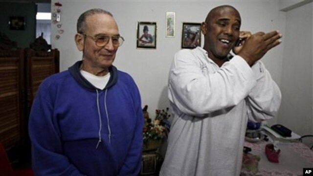 Cuba's dissident Angel Moya, right, speaks on the phone next to fellow dissident Hector Maseda, left, after being released from jail in Havana, Cuba, February 12,  2011.
