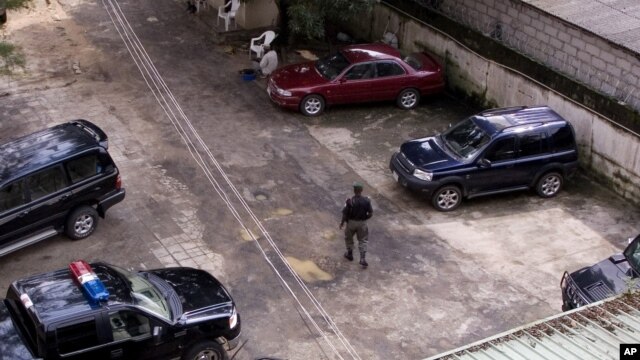 FILE - An unidentified policeman provides security inside the compound of a wealthy Nigerian man, with cars parked ready to provide armed convoys, and the compound protected by high walls and barbed wire in Port Harcourt, Nigeria, July 27, 2007.