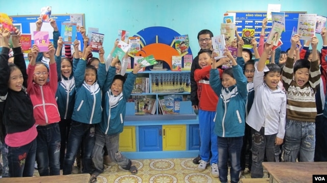 Các học sinh chụp hình phía trước của thư viện với nhà từ thiện Nguyễn Quang Thách tại một trường tiểu học trong tỉnh Thái Bình, Việt Nam (M. Brown / VOA)