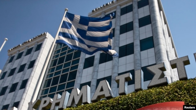 FILE - A Greek flag flutters outside the Athens stock exchange, Greece.