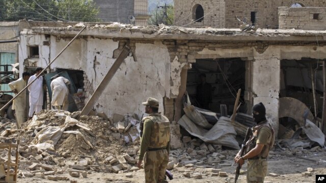 Pakistani men check the damage caused by a car bomb explosion at the site in the town of Darra Adam Khel in the troubled Khyber Pakhtunkhwa province bordering Afghanistan, October 13, 2012. 