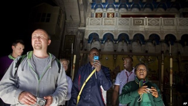 A Nigerian tourist, center, takes a picture as he exits the Church of the Holy Sepulcher, the site traditionally believed by Christians to be the tomb of Jesus, in Jerusalem's Old City, 27 Dec 2010