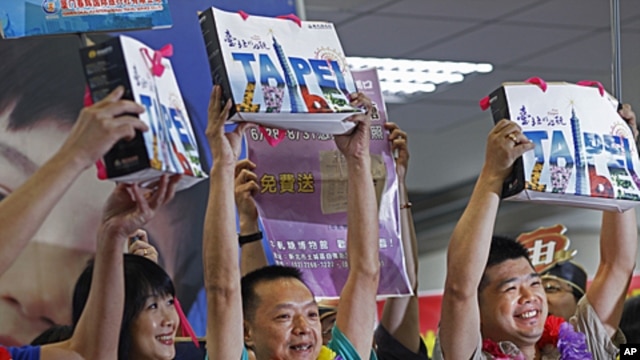 The first individual Chinese tourists hold up gift bags as they arrive at the Songshan airport in downtown Taipei, Taiwan,  June 28, 2011