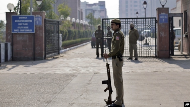 A Delhi policeman stands guard near the gate of a district court where the accused in a gang rape are undergoing trial, in New Delhi, India, January 24, 2013. 