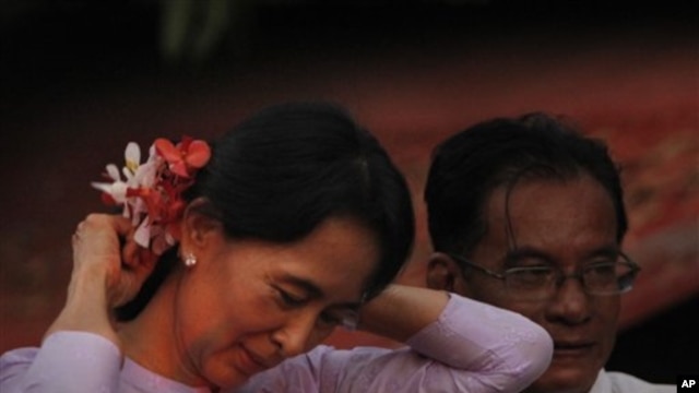 Myanmar's pro democracy leader Aung San Suu Kyi, places flowers from a supporter in her hair after her release from house arrest in Rangoon, Burma, 13 Nov 2010