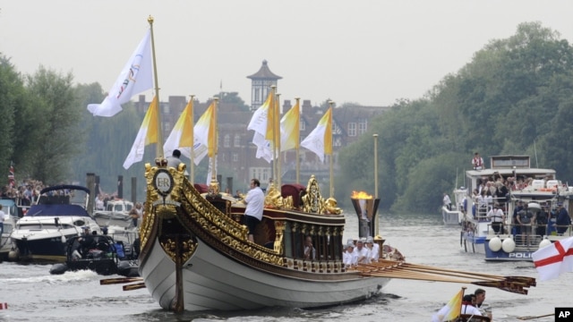 This photo provided by LOCOG shows the royal barge Gloriana carrying Olympic flame burning in the cauldron as it makes its way down the River Thames towards Richmond Bridge during the final day of the Olympic torch relay in London, July 27, 2012. 
