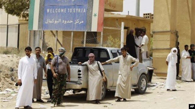 Armed Syrian rebels stand guard as refugees flee Syria at border crossing near Qaim, Iraq, July 25, 2012.