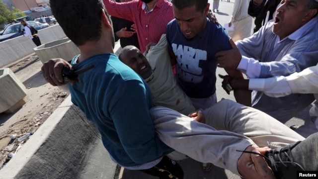 People carry a man who was injured when Libyan militiamen opened fire into a crowd of protesters in Tripoli, Nov. 15, 2013. 
