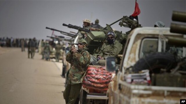 A Libyan rebel scans the field as they wait for the signal to advance at an intersection just outside Brega, April 3, 2011
