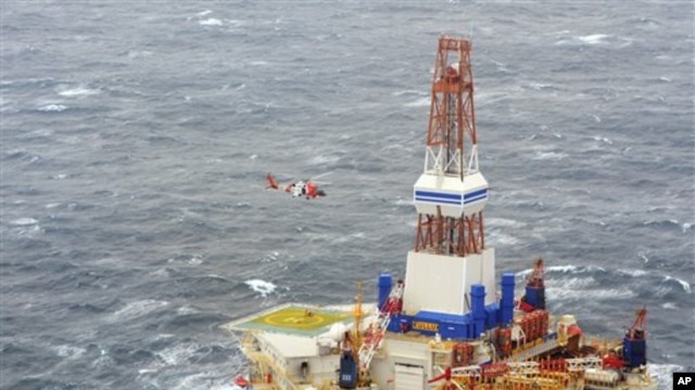 Dari foto yang dirilis oleh Pengawas Pantai Amerika ini, nampak sebuah helikopter dari pangkalan Kodiak tengah memberikan instruksi kepada 18 awak anjungan nomor 13 pengeboran minyak Kulluk (29/12). Anjungan milik perusahaan minyak Shell ini terlepas dari kapal yang menanganinya di laut yang berombak besar Teluk Alaska pada Malam Tahun Baru, dan kandas di pantai berbatu-batu pulau Sitkalidak.