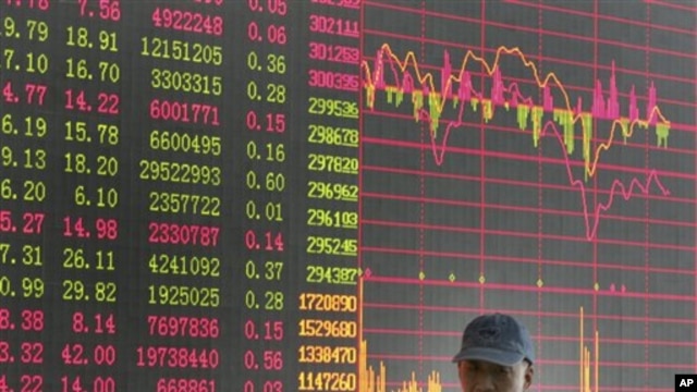 An investor walks past the stock price monitor at a private securities company  in Shanghai, China, 21 Oct 2010