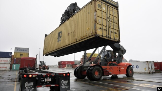 In this photo taken December 18, 2012, a reach stacker operated by a longshoreman (R) places a shipping container on a tractor trailer truck at the Port of Boston, Massachussets.