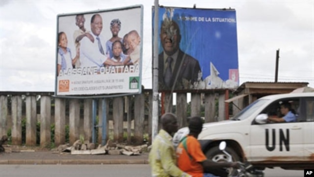 A UN vehicule passes billboards for the presidential electoral campaign on a moped in Bouake, 27 Oct 2010