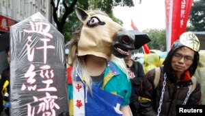 Seorang peserta aksi demo Hari Buruh (May Day) menggunakan topi kuda dan rantai dalam pawai yang melintasi gedung Eksekutif Yuan di pusat kota Taipei, Taiwan (1/5).