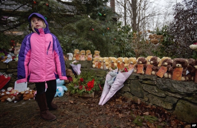 FILE - Ava Staiti, 7, of New Milford, Connecticut, visits a sidewalk memorial with teddy bears representing victims of the Sandy Hook Elementary School shooting in Newtown, Conn., Dec. 16, 2012.