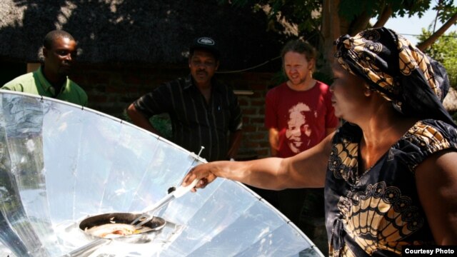 Solar energy champion Crosby Menzies watches a Zambian woman cooking on one of his unique cookers that are powered by the sun (Photo: Sunfire)