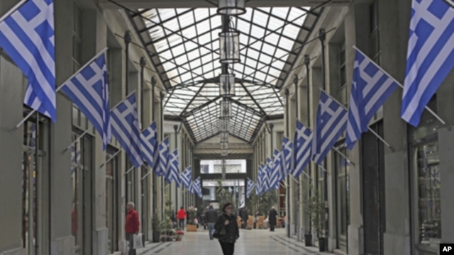 Pedestrian walk inside an arcade full of Greek flags in central Athens, on Wednesday, March 14, 2012. 