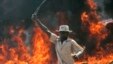 A supporter of the Orange Democratic Party hold up a machete in front of a burning baricade during riots in the Kibera slum in Nairobi, (File photo).