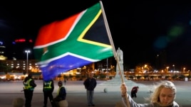 A girl holds a South African national flag as people mourn the death of former President Nelson Mandela outside Cape Town City Hall, where Mandela made his first speech after his release from his 27-year incarceration, Dec. 6, 2013.