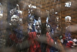 Muslim Brotherhood's Supreme Guide Mohamed Badie (C) waves with the Rabaa sign, symbolizing support for the Muslim Brotherhood, with other brotherhood members at a court in the outskirts of Cairo, May 16, 2015.