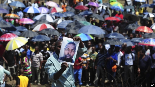A man holds an image of an un-named alleged victim of the recent mining violence during a demonstration in Rustenburg, South Africa, October 6, 2012.  